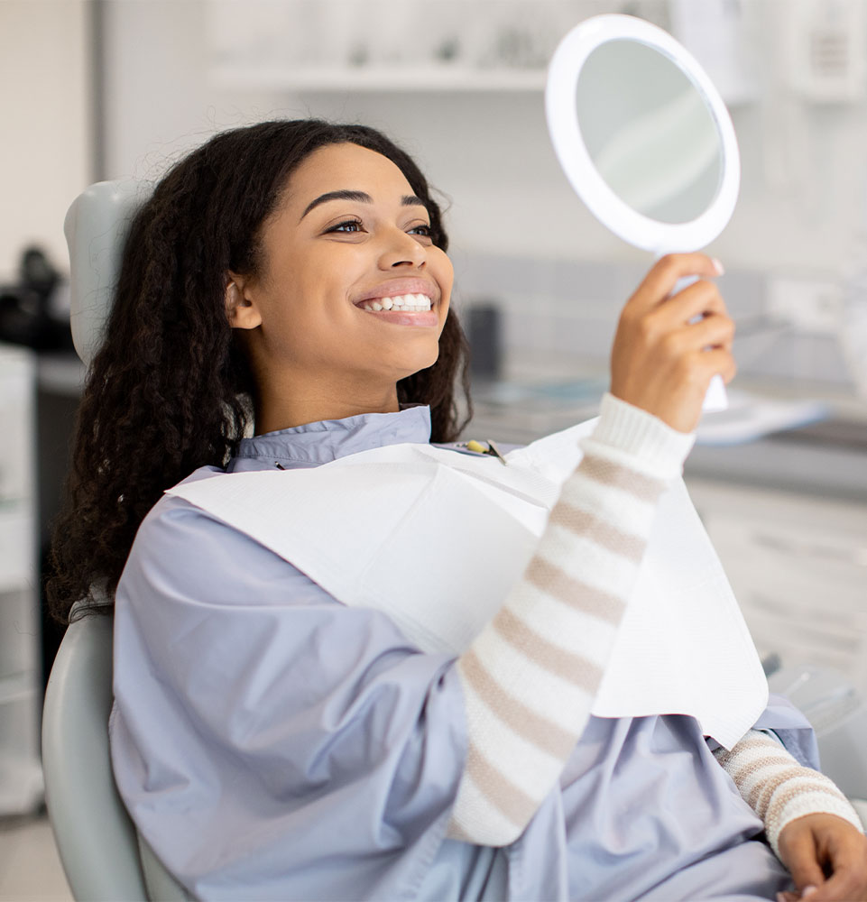 Patient Looking At Mirror After Dental Treatment In Clinic