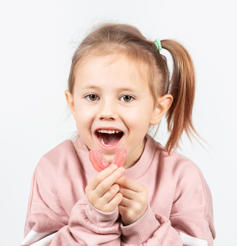 little girl puts myofunctional trainer in the mouth
